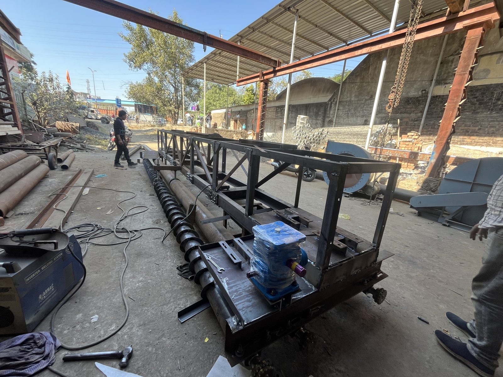 Fixed form concrete paver vibration and screed assembly with auger fitted, outdoor fabrication